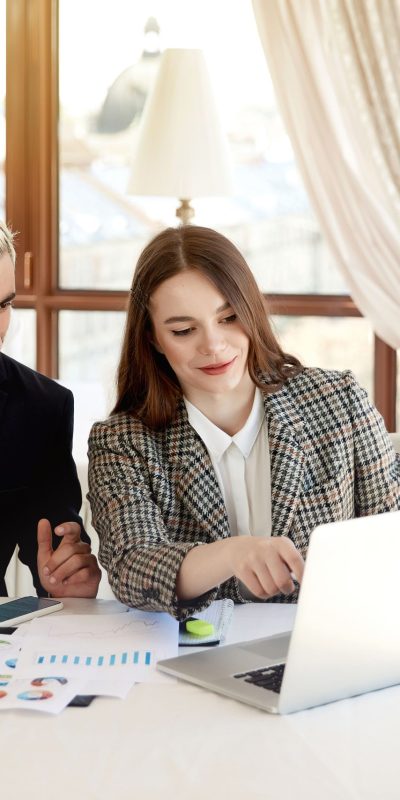 young-blonde-man-brunette-woman-are-looking-computer-discussing-business-plans-min