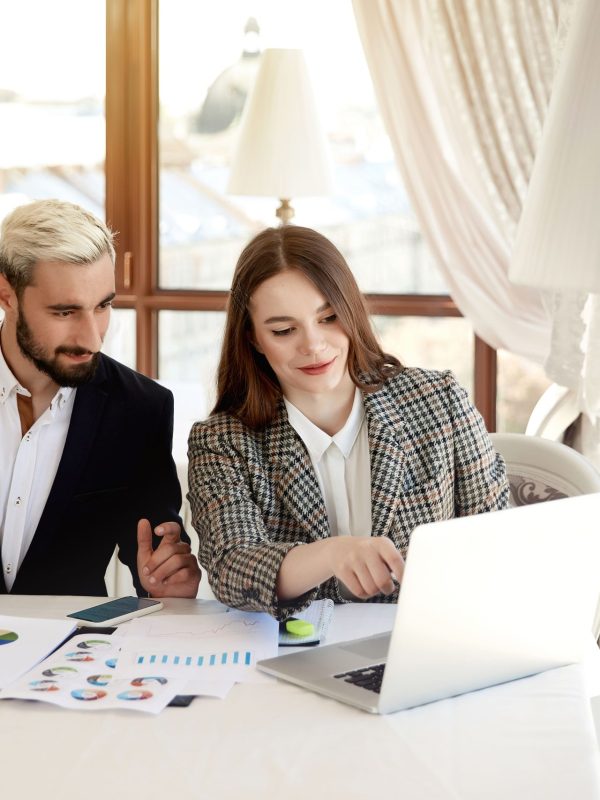 young-blonde-man-brunette-woman-are-looking-computer-discussing-business-plans-min